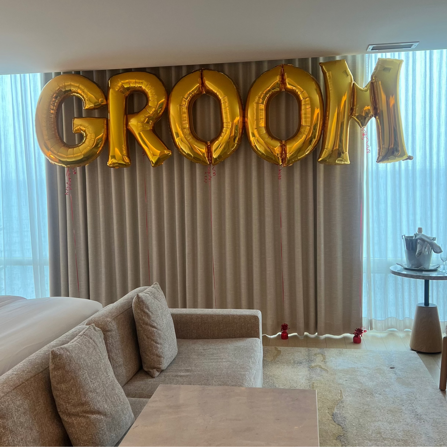 Gold 'GROOM' balloons in a living room setting