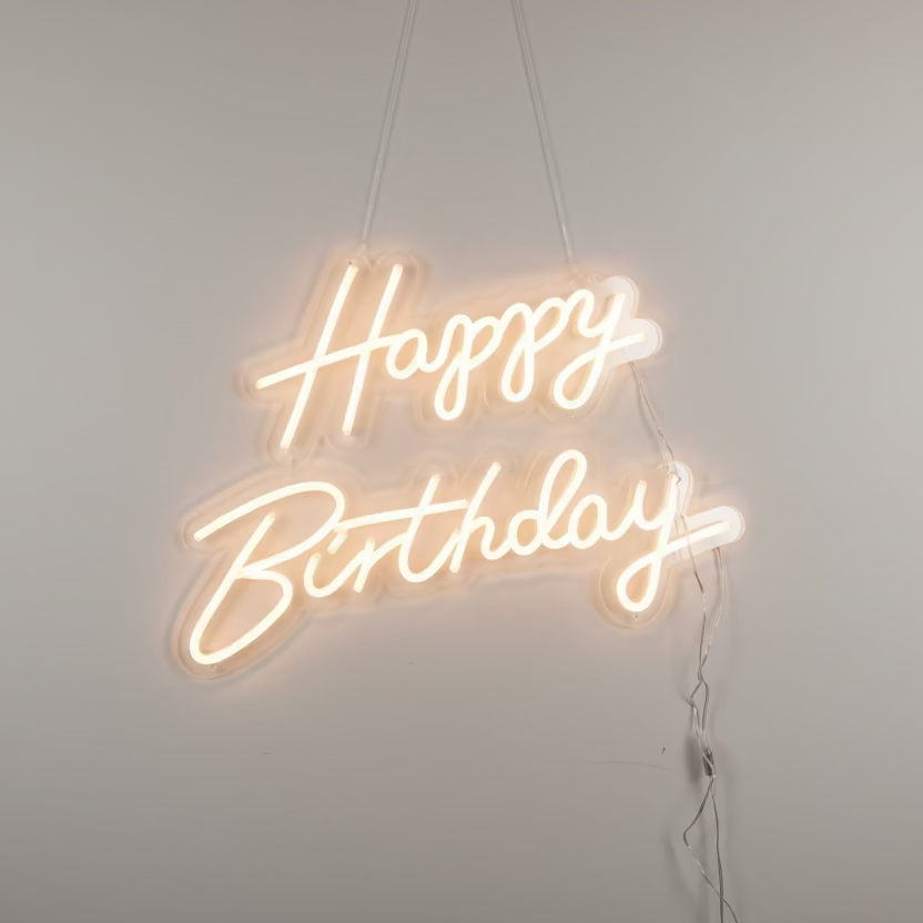 Neon sign with 'Happy Birthday' text on a brown background