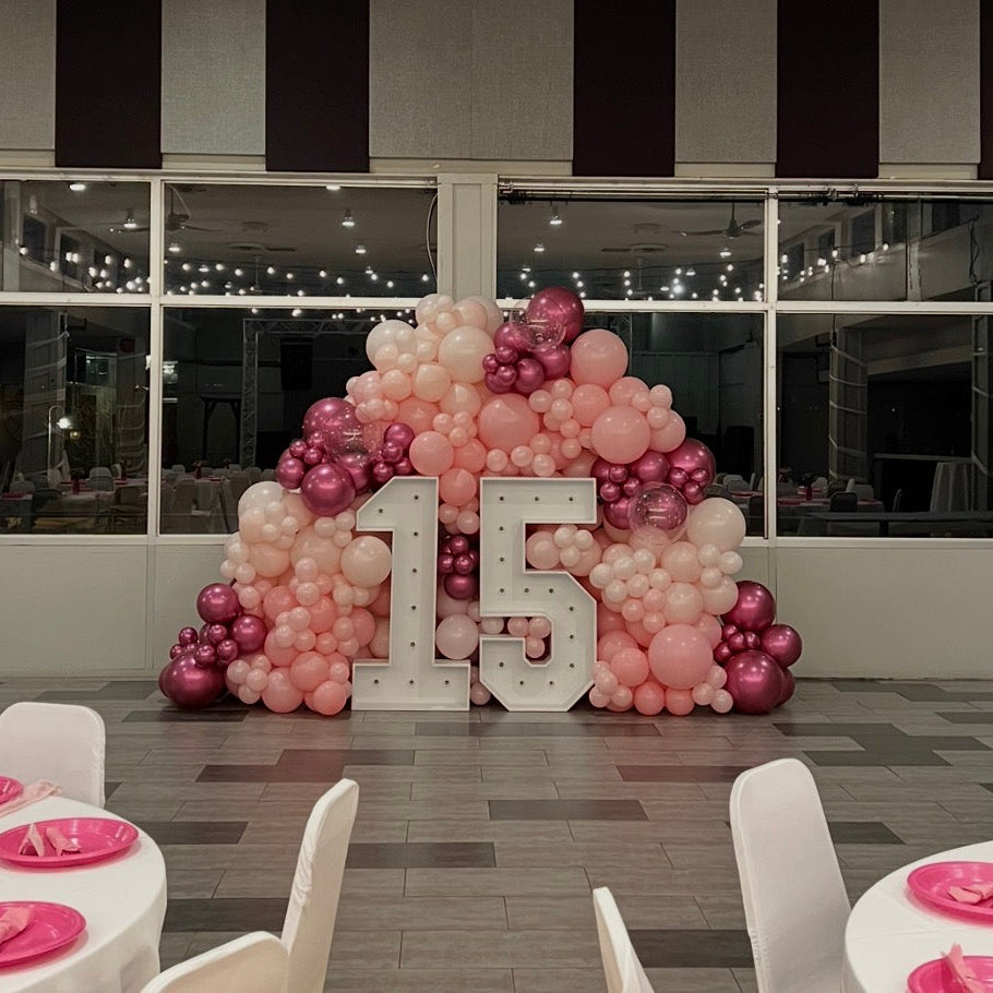 Decorative setup with balloons and '15' for a special event in a room with large windows.