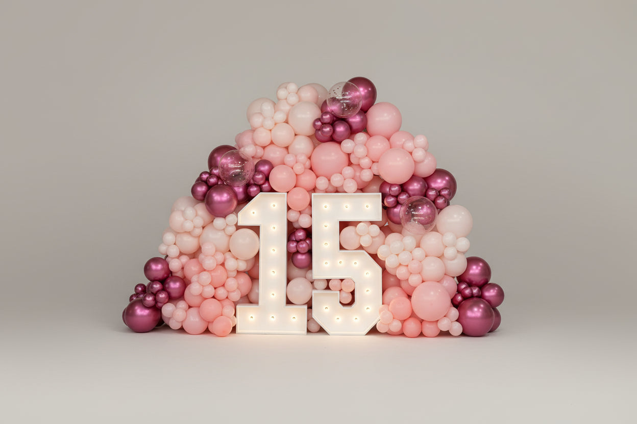 Decorative arrangement of pink and purple balloons with a large '15' in the center on a light gray background.