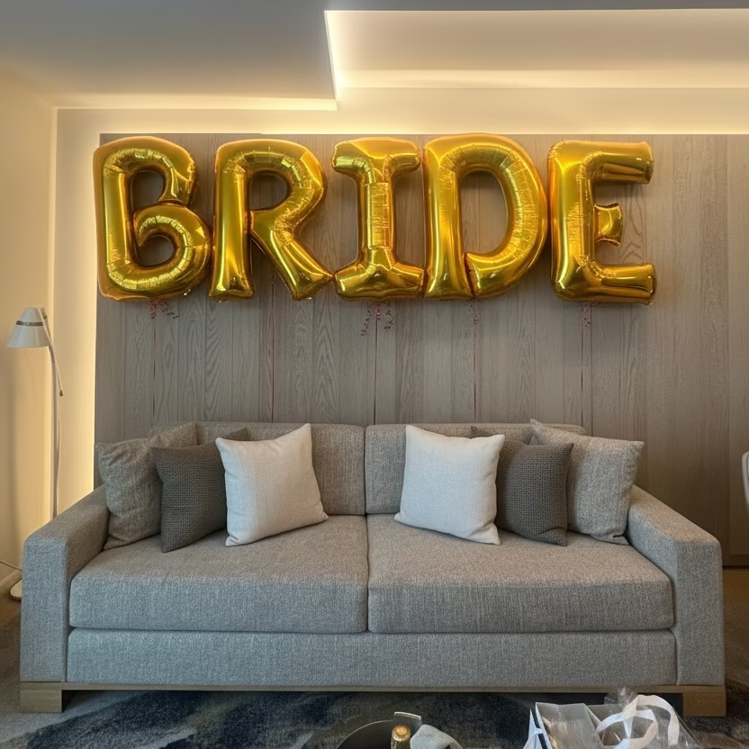 Gold 'BRIDE' balloons in a living room setting with a couch and decor.