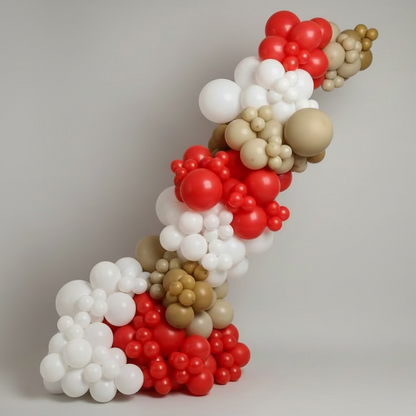 Balloon arch with red, white, and gold balloons in a room with a teddy bear and 'ONE' blocks.