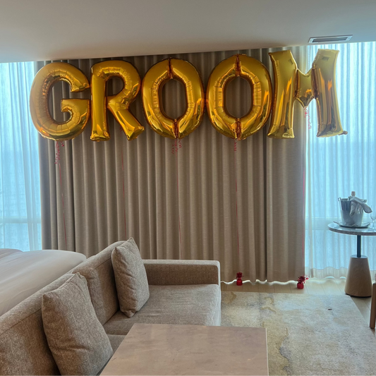 Gold 'GROOM' balloons in a living room setting