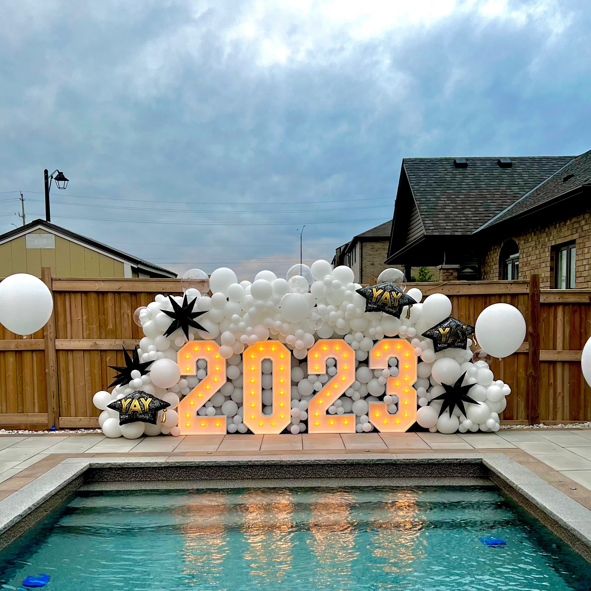 Decorative setup with '2023' letters by a poolside on a cloudy day.