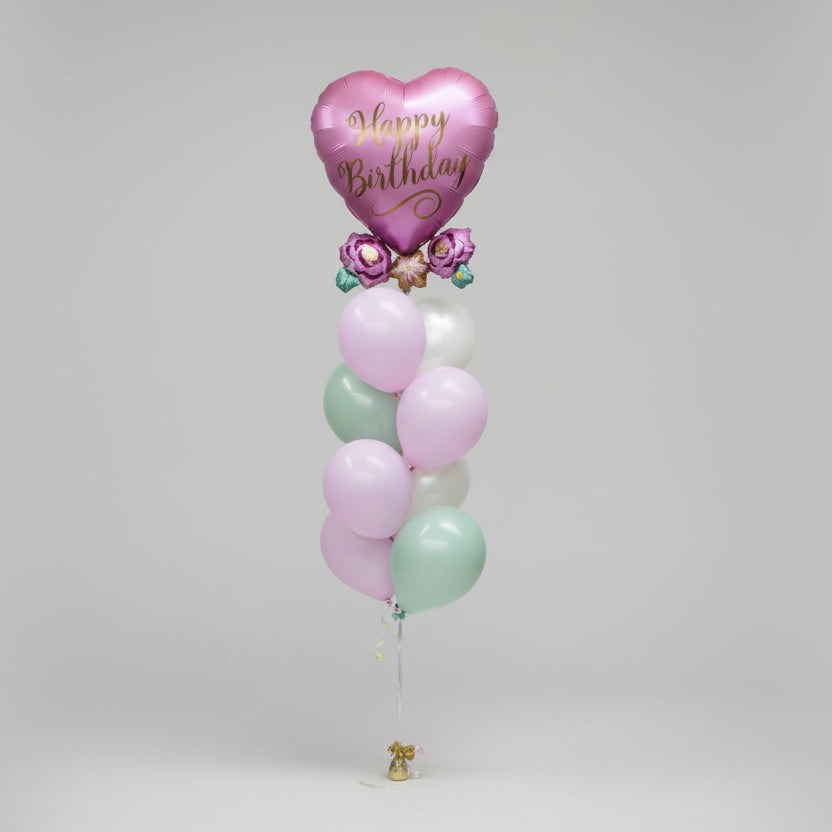 Pastel-colored balloons with a heart-shaped 'Happy Birthday' balloon on a light pink background