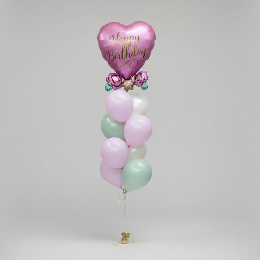 Pastel-colored balloons with a heart-shaped 'Happy Birthday' balloon on a light pink background