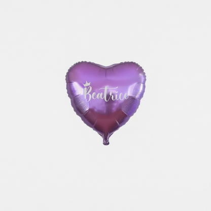 Heart-shaped purple balloon with 'Beatrice' printed on it against a tinsel curtain background.