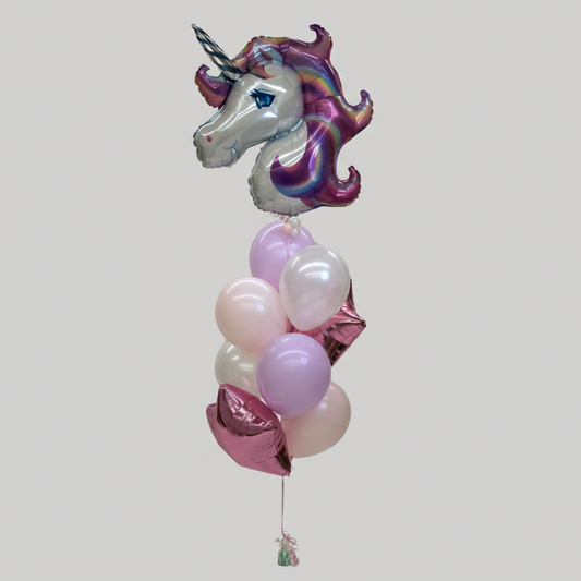 A balloon bundle featuring a large unicorn-shaped foil balloon, with a mane of multicolored confetti and a horn, surrounded by pink and white round balloons.